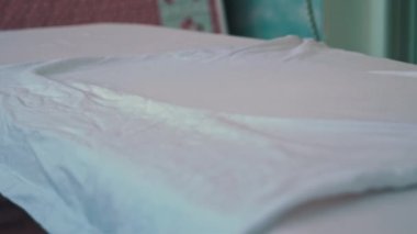 Demir ağır çekimde buhar yayar. Genç bir kadın ütü masasında giysileri ütülüyor. Bir ev hanımı rutin ev işlerini yapar. İşlerle ilgilenmek ve onları düzene sokmak..