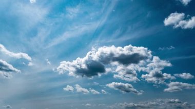 White fluffy clouds slowly float through the blue daytime sky timelapse. Beautiful skies are moving. Airy snow-white clouds move to the side.