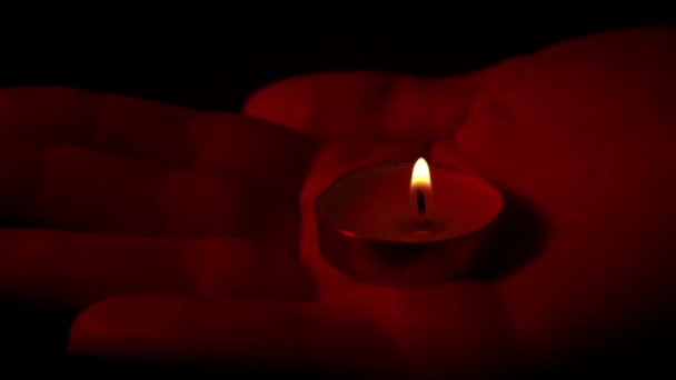 在红色灯火的特写下 人们手握一支蜡烛 石蜡蜡蜡烛在黑暗中与黄色的火焰一起燃烧 房子里没有灯 是蜡烛发出的热 沉默的时刻 — 图库视频影像