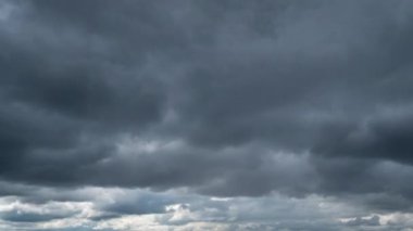 Zaman ayarlı gri yağmurlu bulutlar bulutlu bir günde karanlık gökyüzünde yüzerler. Bulutlu gökyüzü ve kasvetli bulutlar. Yağmurlu havada büyülü dramatik gökyüzü. Uğursuz bulutlar gökyüzünde yavaşça sürükleniyor, yağmuru tehdit ediyor..