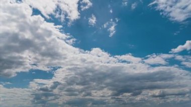 White fluffy clouds slowly float through the blue daytime sky timelapse. Beautiful skies are moving. Airy snow-white clouds move to the side.