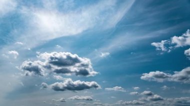 White fluffy clouds slowly float through the blue daytime sky timelapse. Beautiful skies are moving. Airy snow-white clouds move to the side.