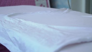 Demir ağır çekimde buhar yayar. Genç bir kadın ütü masasında giysileri ütülüyor. Bir ev hanımı rutin ev işlerini yapar. İşlerle ilgilenmek ve onları düzene sokmak..