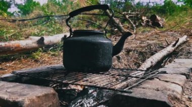 Tencere dibin kara seninki benden kara, seninki benden kara. Ormanda piknik. Çaydanlık yanıyor ve su kaynatıyor. Bir çaydanlık odun ateşinde ısıtılır..