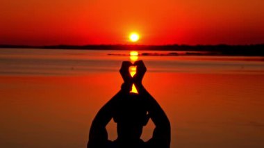 Gün batımında tek başına elini kaldırmış bir adamın siluetleri. Dalgın bir adam gün batımında suyun yanında oturur. Hayalci bir adamın silueti turuncu gökyüzüne büyük bir güneşle bakıyor..