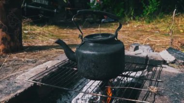 Tencere dibin kara seninki benden kara, seninki benden kara. Ormanda piknik. Çaydanlık yanıyor ve su kaynatıyor. Bir çaydanlık odun ateşinde ısıtılır..