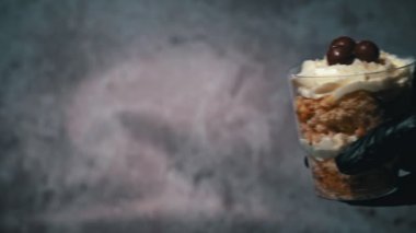Şekerci şeffaf bardaklarda küçük kekler topluyor. Gözlüklü lezzetli kekler. Bardakta tatlı hazırlıyorum. Ev yapımı şekerleme. Siyah eldivenli eller önemsiz bir pasta yapar..