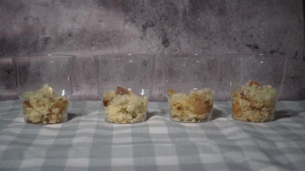 コンセカンドは透明なカップで三艦ケーキを収集する メガネの中の美味しいケーキ デザートをグラスで準備する ホーム 黒い手袋の手は トリフケーキを作る — ストック動画