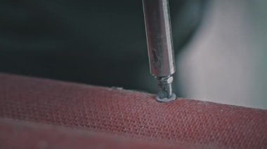 Ağır çekimde tornavidayla sıkışan bir çivinin yakın çekimi. Erkek eli vidaya sokulur. Erkek ev işi. Bir işçi vidayı sıkar. Marangozluk ve inşaat işleri yakın plan..