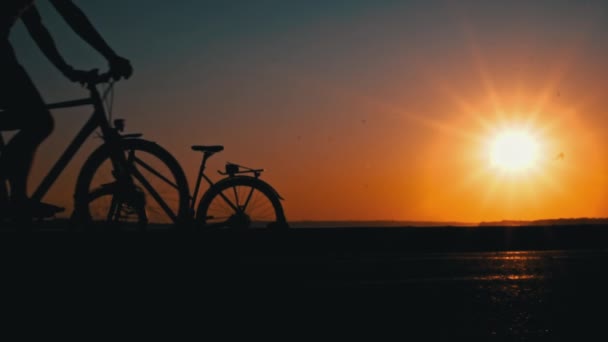 夕日だけで自転車に乗っている男のシルエット ペンシルベニア州の男は日没時に水の近くに座っている 男の夢のようなシルエットは 大きな座っている太陽とオレンジ色の空を見ます — ストック動画