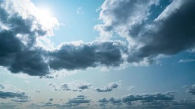 White fluffy clouds slowly float through the blue daytime sky timelapse. Beautiful skies are moving. Airy snow-white clouds move to the side.