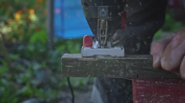 Adam tahtada yapbozla çalışıyor. Ellerinde elektrikli yapboz olan usta marangozun elleri odun kesiyor. Eller odun kesmek için yapboz kullanır. Atölyede yapbozla odun kesmek.