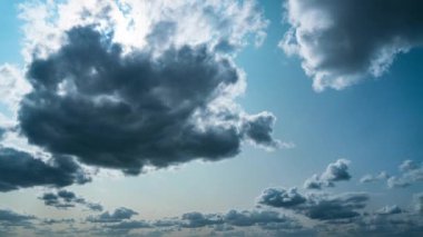 White fluffy clouds slowly float through the blue daytime sky timelapse. Beautiful skies are moving. Airy snow-white clouds move to the side.