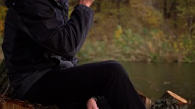 Erkek eller sonbahar atmosferinde yakın çekim bir bardak kahve alır. Genç bir adam parkta yürürken kahve içer. Yaşam tarzı. Sonbahar yürüyüşü konsepti.