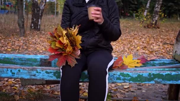 在秋天的气氛中 女人在杯子里喝着咖啡 一个小女孩在公园里散步的时候喝咖啡 生活方式 秋天散步的概念 — 图库视频影像