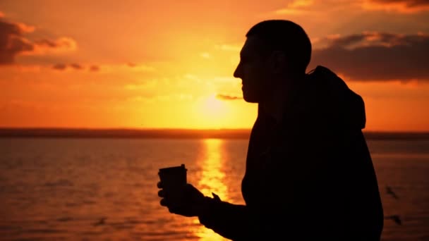 夕阳西下的轮廓人在长椅上喝咖啡 在自然界的夜晚 芬芳的咖啡 一个人在日落时喜欢喝咖啡 与自然独处的思想 自由思考的概念 — 图库视频影像