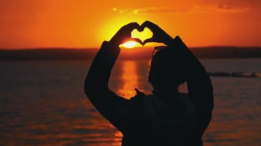 Kız, kalbini batan güneşe siluet içinde gösterir. Bir kadın gün batımına tek başına bakar. Doğayla baş başa düşünceler. Serbest düşünce konsepti.