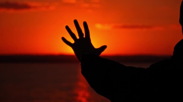男は手を差し伸べ 太陽が沈むシルエットに向かって手を伸ばした 人は夕日だけを見つめている 自然とひとりで考える 自由思考コンセプト — ストック動画