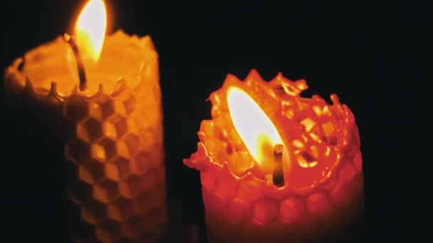 黒い背景に2本の蝋燭が燃えています キャンドルライトイエローライト 大きなワックスキャンドル火災は黄色を燃やします 家には灯りがない 暖かさはろうそくから来ている 沈黙の瞬間 — ストック動画