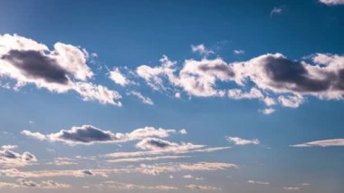 Beyaz kabarık bulutlar mavi gündüz vakti gökyüzünde yavaşça süzülür. Güzel gökyüzü hareket ediyor. Kar beyazı bulutlar yana doğru hareket ediyor..