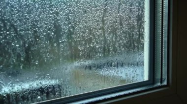 Bulutlu havada pencere camından yağmur damlaları akar. Yağmurlu bir hava. Sisli pencereden aşağı buhar akıyor. Üzücü depresif ruh hali. Islak ve soğuk mevsim.