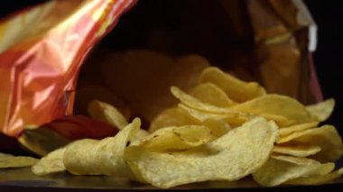 Kıtır kıtır patates cipsi, yakın plan çekimde. Sağlıksız fast food için patates çerezi. Siyah arka planda kaotik bir şekilde saçılmış çipler. Abur cubur, fast food. Kızarmış patatesler yakın..