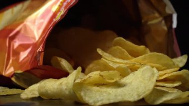 Kıtır kıtır patates cipsi, yakın plan çekimde. Sağlıksız fast food için patates çerezi. Siyah arka planda kaotik bir şekilde saçılmış çipler. Abur cubur, fast food. Kızarmış patatesler yakın..