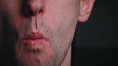 Adam siyah arka planda yavaş çekimde yemek çiğniyor. Yemekten zevk alan bir adamın yüzü. Kişi yavaşça çiğner..