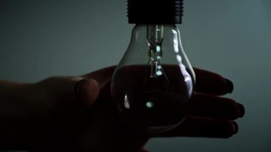 Light bulb turns on and goes out at the touch of a persons hand in the dark. Slow turning on and off of a tungsten light bulb. Filament of a blinking vintage light bulb. Energy, electricity, light