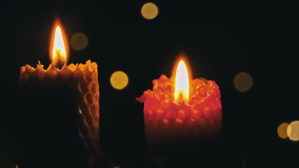 两支蜡蜡烛在黑色的背景上燃烧 蜡烛点亮淡黄色的灯 巨大的蜡火燃烧黄色 房子里没有光 温暖来自蜡烛 沉默一分钟 — 图库视频影像