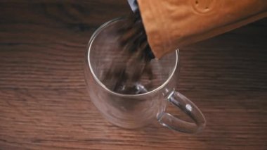 El işi paketindeki kahve çekirdekleri fincana düşer. Kavrulmuş kahverengi kahve çekirdekleri. Koyu kavrulmuş Arap kahve çekirdekleri düşüyor. Kavrulmuş aromatik kahve..