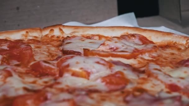 サラミとベーコンのあるピザが黒い背景の箱に回転する 肉とチーズで新鮮なピザを添えています イタリア製のピザサイド ファストフード — ストック動画