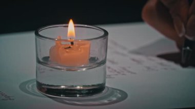 Mans yakın plan beyaz kağıt üzerine antika bir kalem ile el yazısı. Kalem ve mürekkeple beyaz bir kağıda yazı kalemi ve mürekkep yazmış. Mum ışığında büyük harflerle bir mektup yaz..