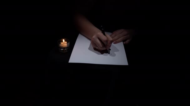 ハンドはキャンドルライトで暗い部屋に白い紙にペンで書きます 白紙にアンティークペンとインクを用いて書道を執筆する 首都の手紙に手紙を書く — ストック動画