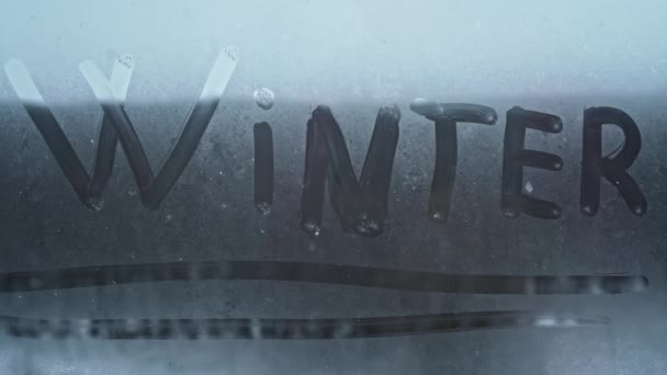 Επιγραφή Χειμώνας Ένα Δάχτυλο Στο Παγωμένο Παράθυρο Κατά Διάρκεια Χιονοθύελλας — Αρχείο Βίντεο