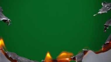 White paper burns from above on a green background copy space. The sheet of paper burns and reveals a green background for pasting.