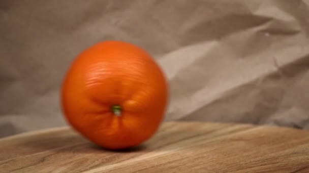 木の表面のローリング オレンジ 新鮮でジューシーなオレンジ色の木製の表面に ひび割れた紙の背景に動きを捉える — ストック動画
