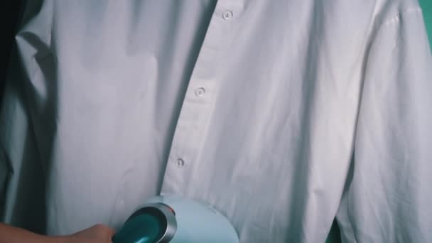 ハンドヘルドスチームアイアンスムージーホワイトシャツは アクションで蒸気鉄を描き 鮮明な外観のために白いシャツからしわを取り除きます — ストック動画
