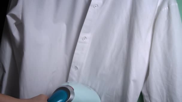 ハンドヘルドスチームアイアンスムージーホワイトシャツは アクションで蒸気鉄を描き 鮮明な外観のために白いシャツからしわを取り除きます — ストック動画