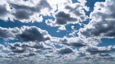 White fluffy clouds slowly float through the blue daytime sky timelapse. Beautiful skies are moving. Airy snow-white clouds move to the side.