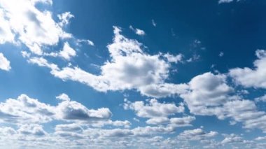 Beyaz kabarık bulutlar mavi gündüz vakti gökyüzünde yavaşça süzülür. Güzel gökyüzü hareket ediyor. Kar beyazı bulutlar yana doğru hareket ediyor..