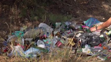 Ormanda yere saçılmış çeşitli çöp türlerinin yakın çekim görüntüsü. Olay yeri plastik şişeleri, teneke kutuları ve diğer çöpleri yakalıyor. Bu görüntü sorunu açıklamak için mükemmel.
