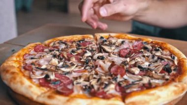 Yakın plan çekimde bir dilim pizza ile salam, mantar ve pastırma..