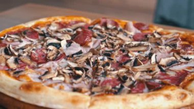 Mantarlı, salamlı ve pastırmalı bir pizzanın yakın plan çekimi. Bu görüntüler yemek blogları, reklamlar ve sosyal medya paylaşımları için mükemmel..