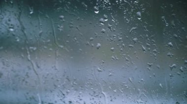 Cam bir yüzeyde yağmur damlacıklarının yakın plan görüntüsü. Yağmurlu bir arka plan gerektiren herhangi bir video projesine karamsar, atmosferik bir his eklemek için mükemmel. Doku örtüsü ya da arkaplan ögesi olarak kullan.