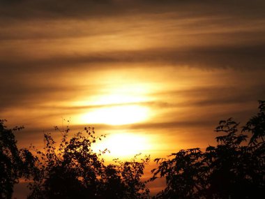 Riga 'nın Bolderaja bölgesinde gün batımında bulutların arasında güneş.
