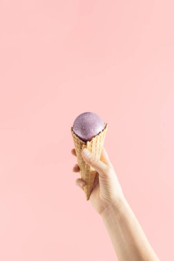 Elde dondurma külahı ve rengarenk pembe arka planda noel ziyafeti ile minimal tatil görüntüsü. Kopya alanı ile yaratıcı bir sahne. Yeni Yıl Estetiği.