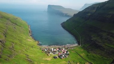 Faroe Adaları 'ndaki Tjornuvik köyünün insansız hava aracı görüntüsü. Çimen çatılı tipik eski Faroe evleri. Çimlerle kaplı ev. Güneşli bir yaz günü. 4k görüntü. 