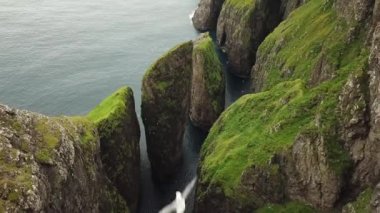Faroe Adaları, Dunnesdrangar 'ın insansız hava aracı görüntüsü. İnanılmaz doğa, Faroe Adaları 'ndaki büyük kayalıklar ve dağlar. Vagar Adası. Bir sürü uçan deniz kuşu. Yazın güneşli bir gün. Yüksek kalite 4k görüntü. 