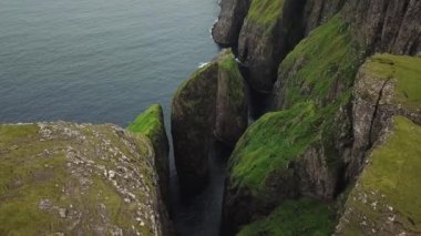Faroe Adaları, Dunnesdrangar 'ın insansız hava aracı görüntüsü. İnanılmaz doğa, Faroe Adaları 'ndaki büyük kayalıklar ve dağlar. Vagar Adası. Bir sürü uçan deniz kuşu. Yazın güneşli bir gün. Yüksek kalite 4k görüntü. 